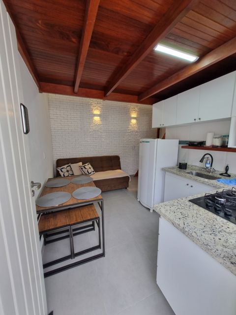 Sala integrada com cozinha, mesa de jantar e sofá-cama